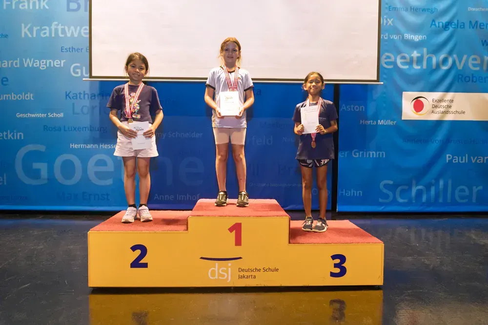 Three young girls are standing on a podium with the number 1 2 and 3 on it