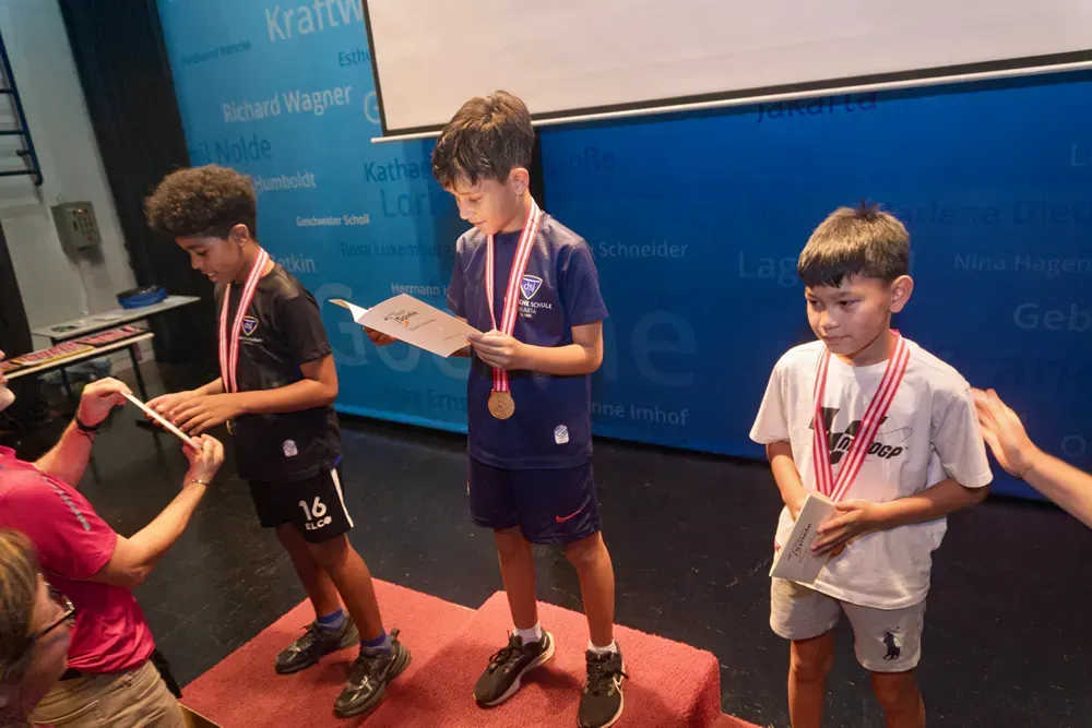 Three young boys are standing on a podium with medals around their necks.