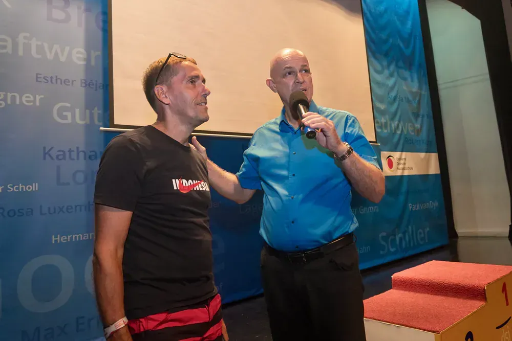 Two men are standing next to each other and one is holding a microphone