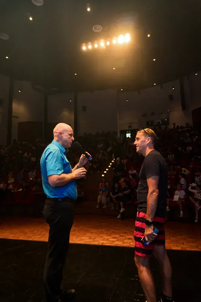 Two men are standing on a stage talking to each other.