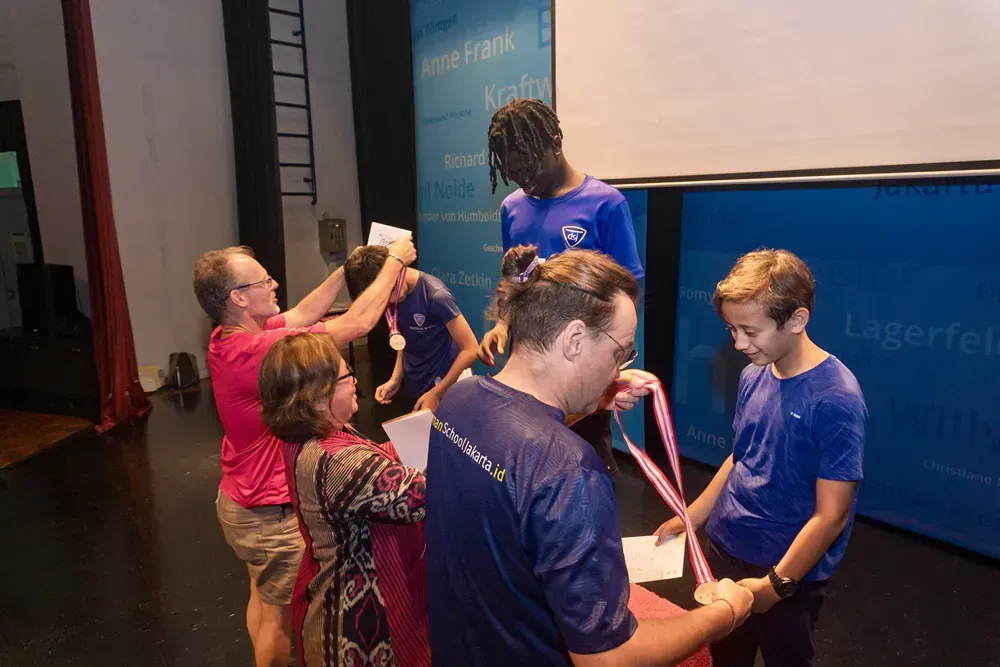 A group of people are standing on a stage holding medals.