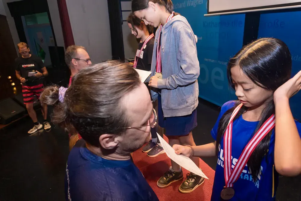 A man is giving a medal to a girl who is wearing a medal around her neck.