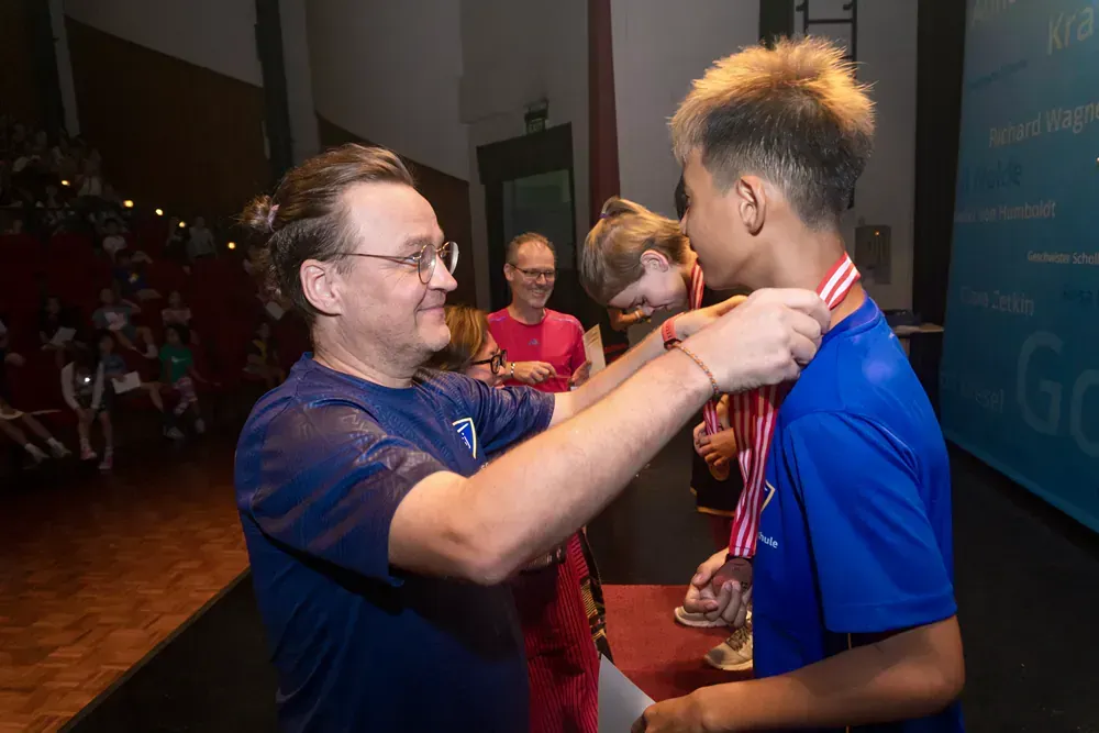 A man is putting a medal on a boy 's neck.