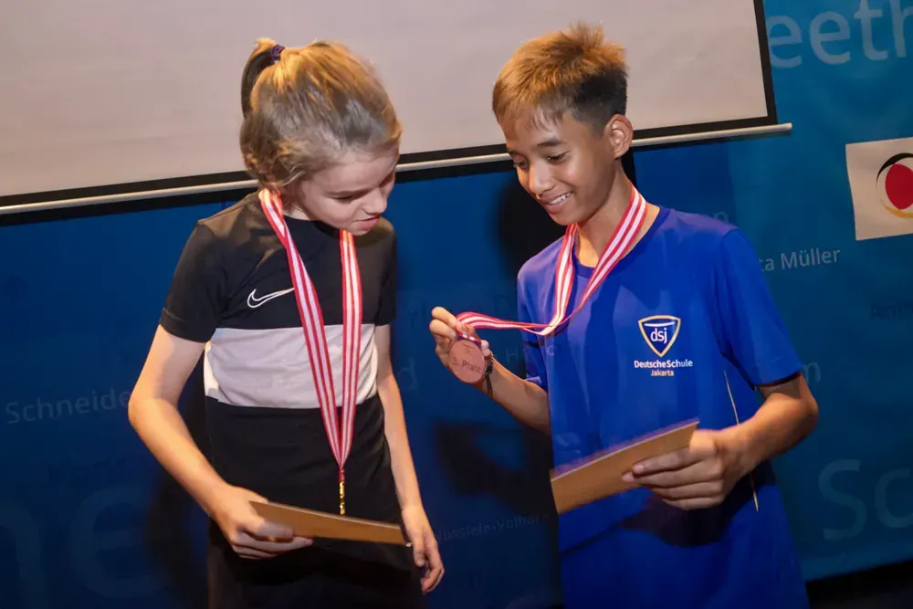A boy and a girl are standing next to each other with medals around their necks.