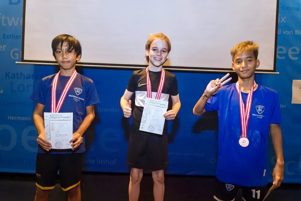 Three young boys standing next to each other with medals around their necks