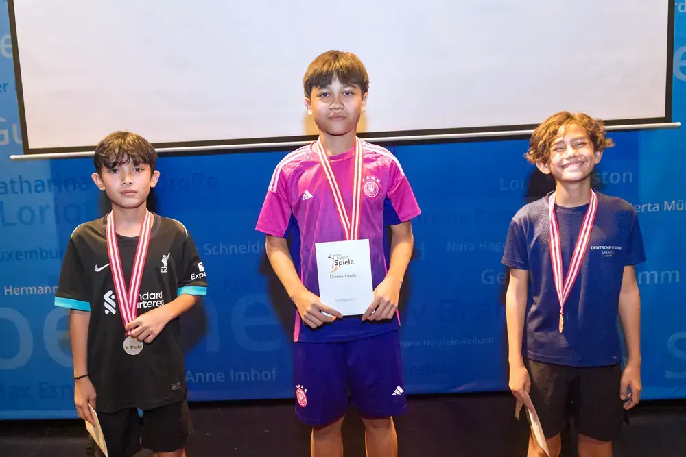 Three young boys are posing for a picture with medals around their necks.