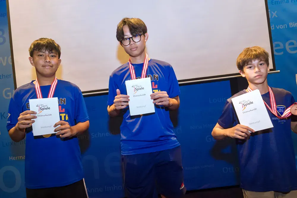 Three boys are standing next to each other holding certificates