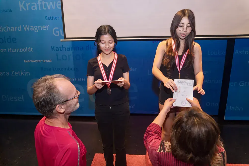 A man is taking a picture of two girls wearing medals