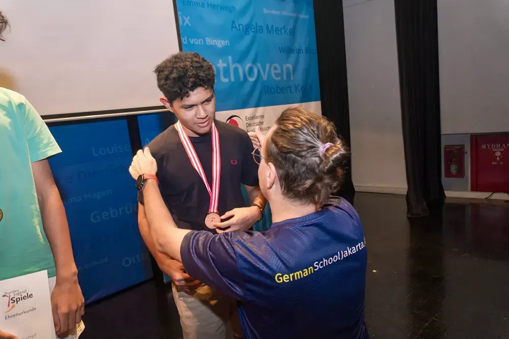 A woman is putting a medal around a man 's neck