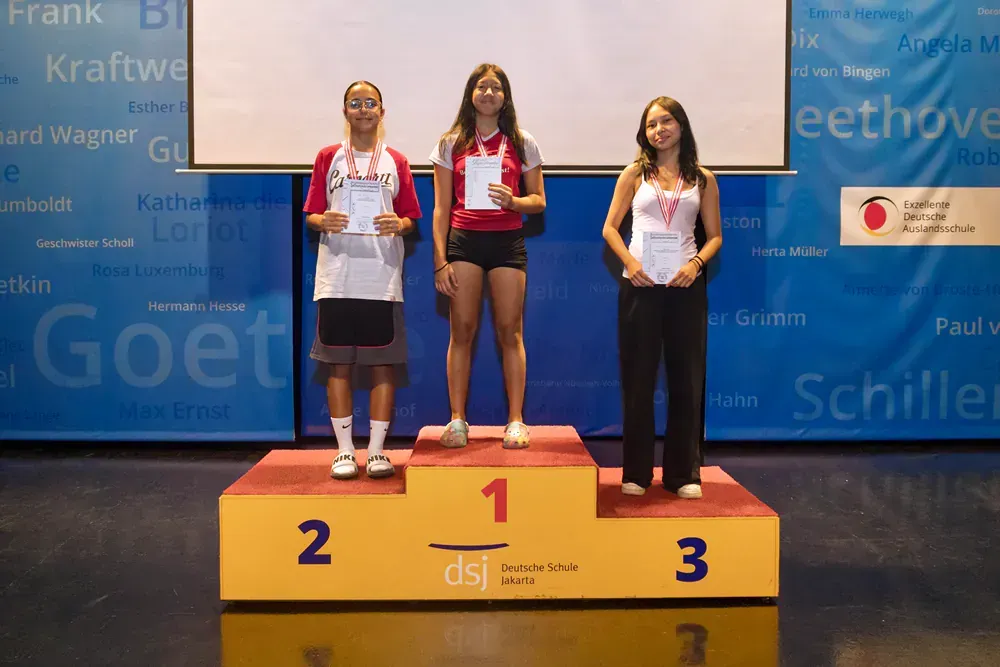Three people standing on a podium with the number 1 2 and 3 on it