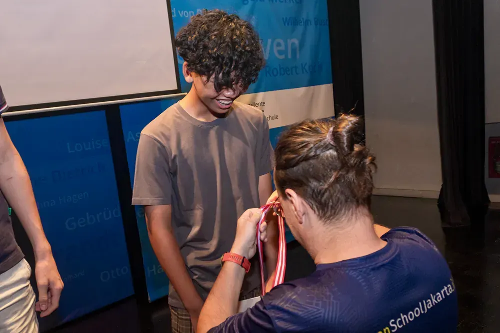 A man is putting a medal around another man 's neck.