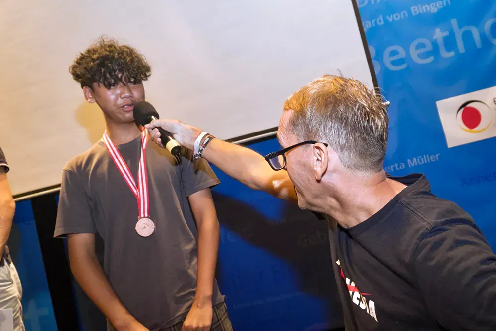 A man is putting a medal around a boy 's neck
