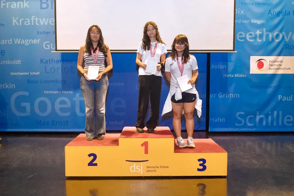 Three women standing on a podium with the number 1 on it