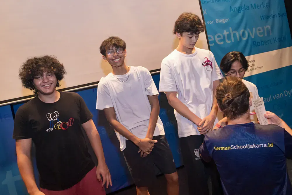 A group of young men are standing next to each other in front of a blue wall.