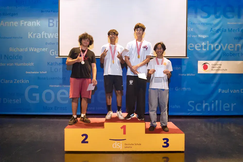 A group of young men are standing on a podium with medals.