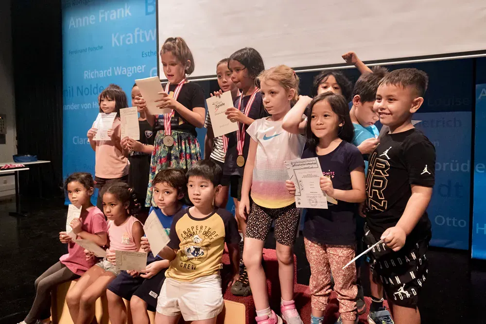 A group of children are standing on a stage holding certificates.
