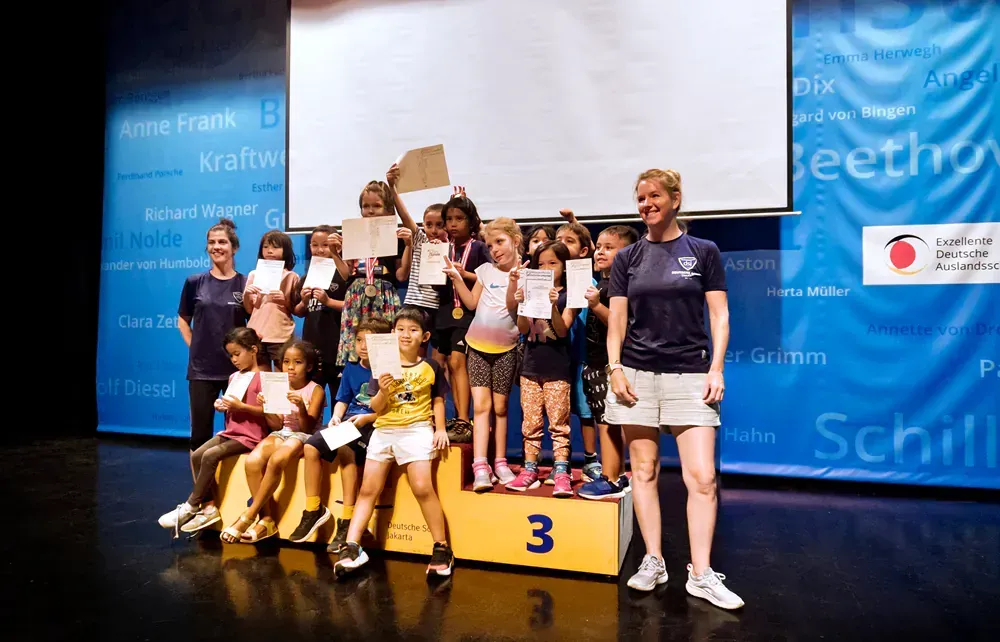 A group of children are standing on a podium with the number 3 on it.