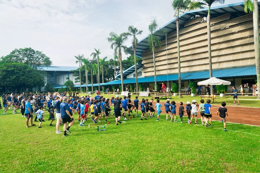 A group of children are running in a field in front of a building.