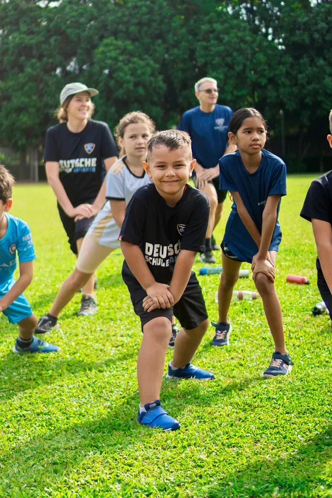 A group of children are doing stretching exercises in a field.