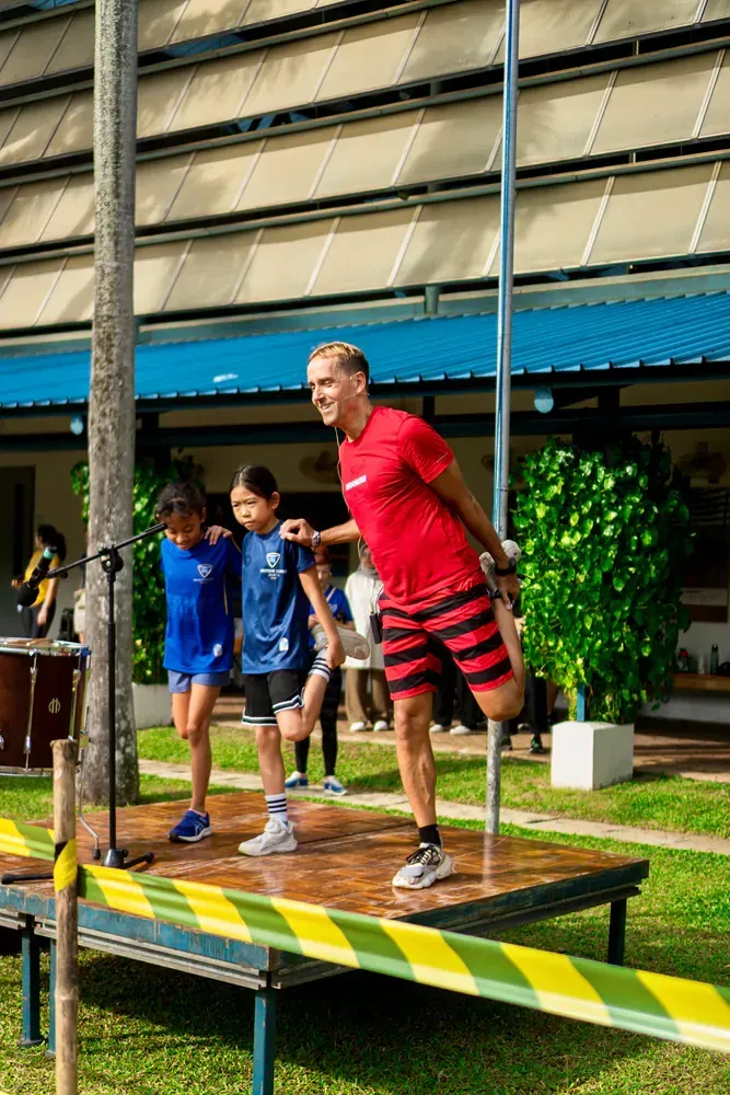 A man in a red shirt is standing on a wooden platform with two children.