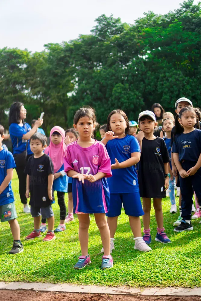 A group of children are standing on top of a lush green field.