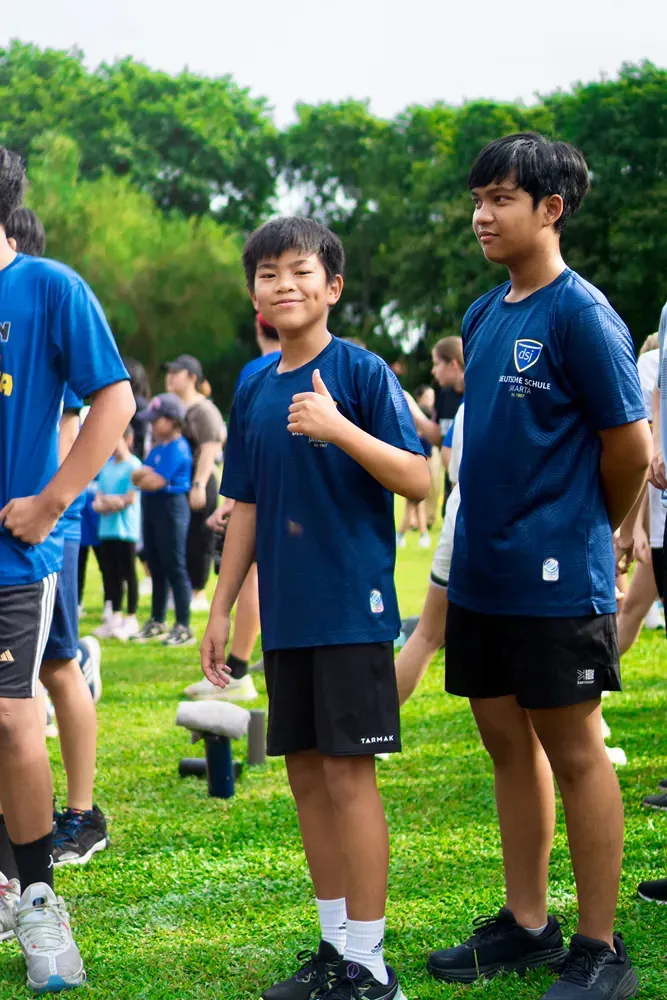 A group of young boys are standing on top of a lush green field.