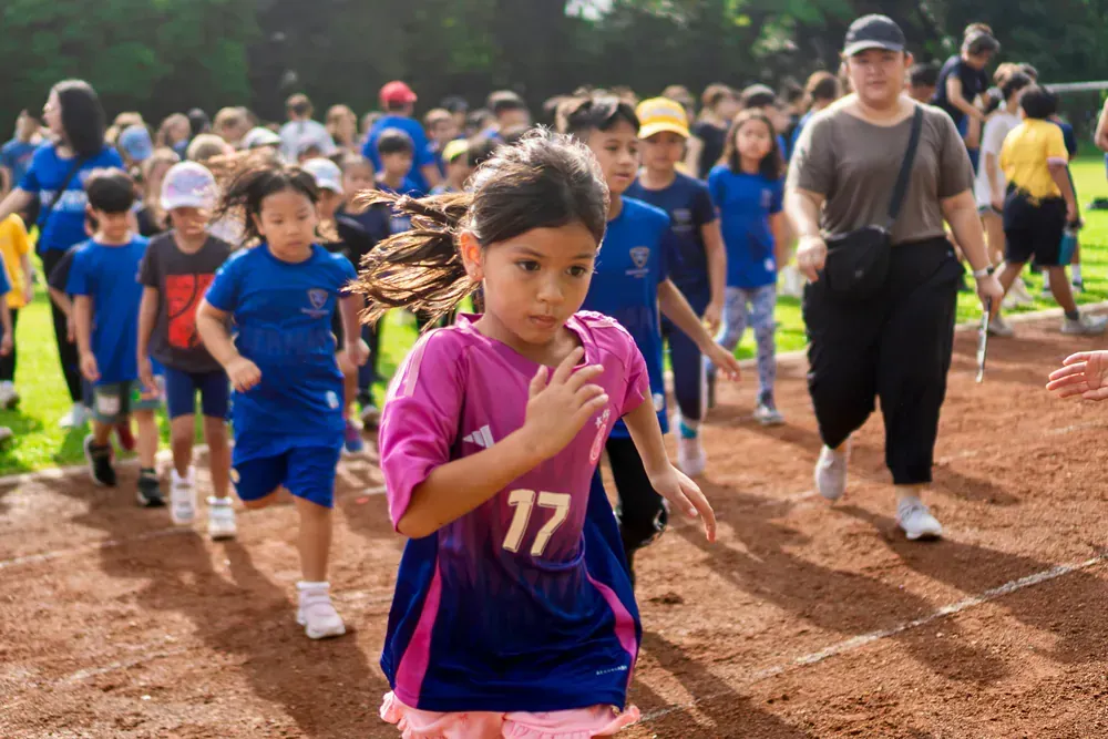 A group of children are running on a dirt track.