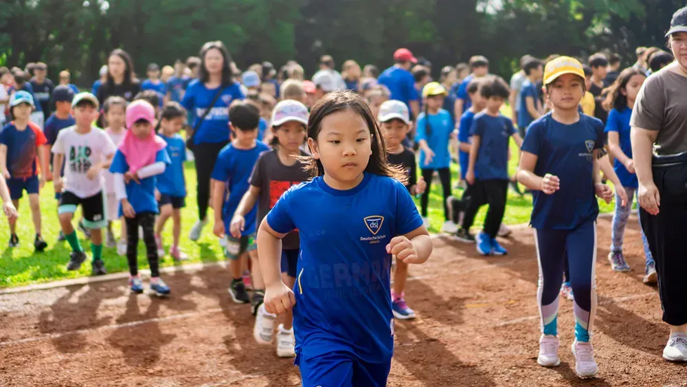 A group of children are running on a dirt track.