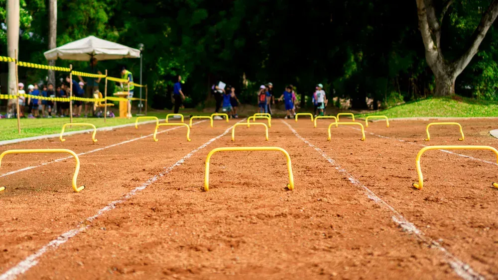 A group of people are running on a track with hurdles.