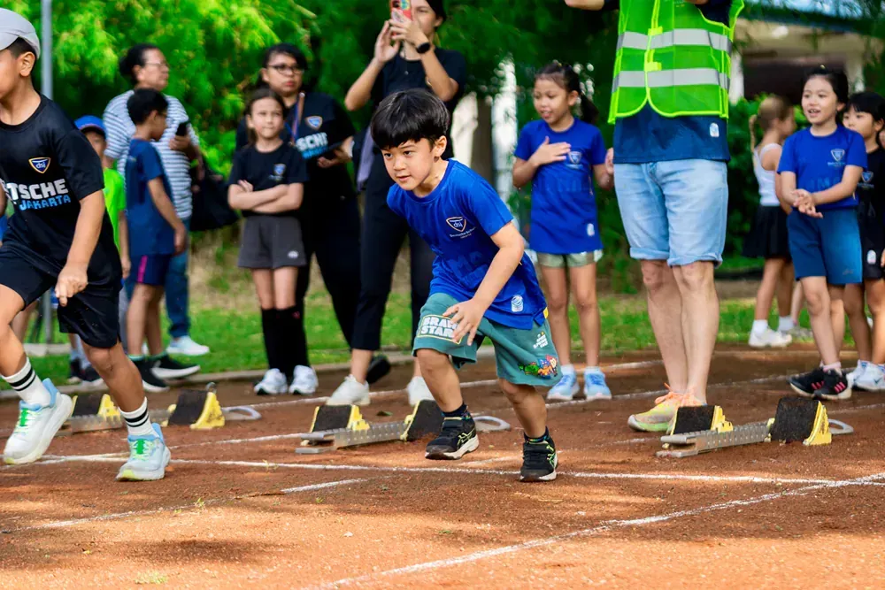 A group of children are running on a track.