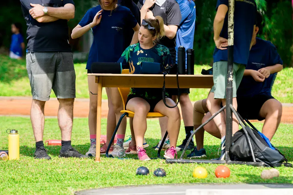 A group of people are sitting at a table in the grass.
