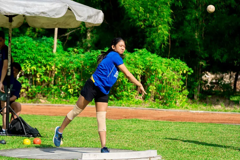 A young girl is throwing a ball on a field.