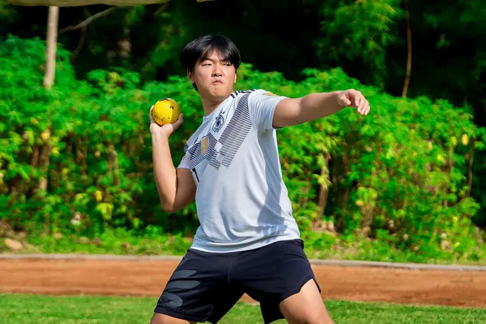 A young man is throwing a ball on a field.