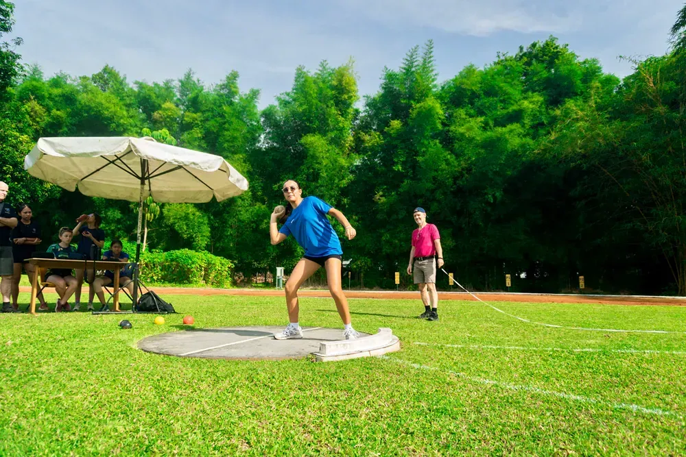 A woman is throwing a shot put in a field.