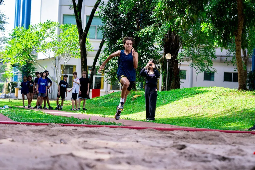 A man is jumping in the air while a group of people watch.