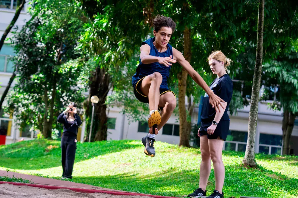 A man is jumping in the air while a woman watches.