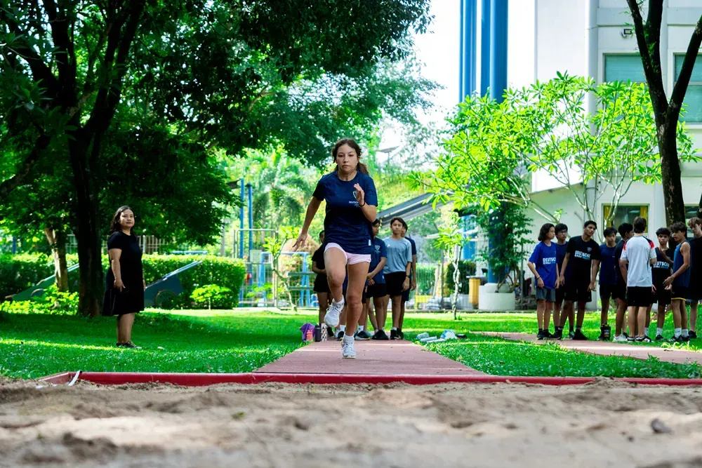 A girl is jumping in the air while a group of people watch.