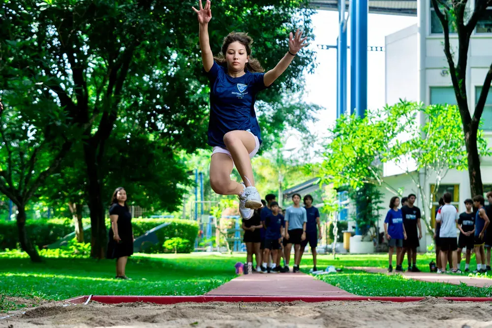 A young girl is jumping in the air while a group of people watch.
