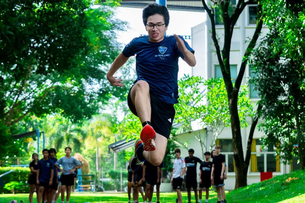 A man is jumping in the air in front of a group of people.