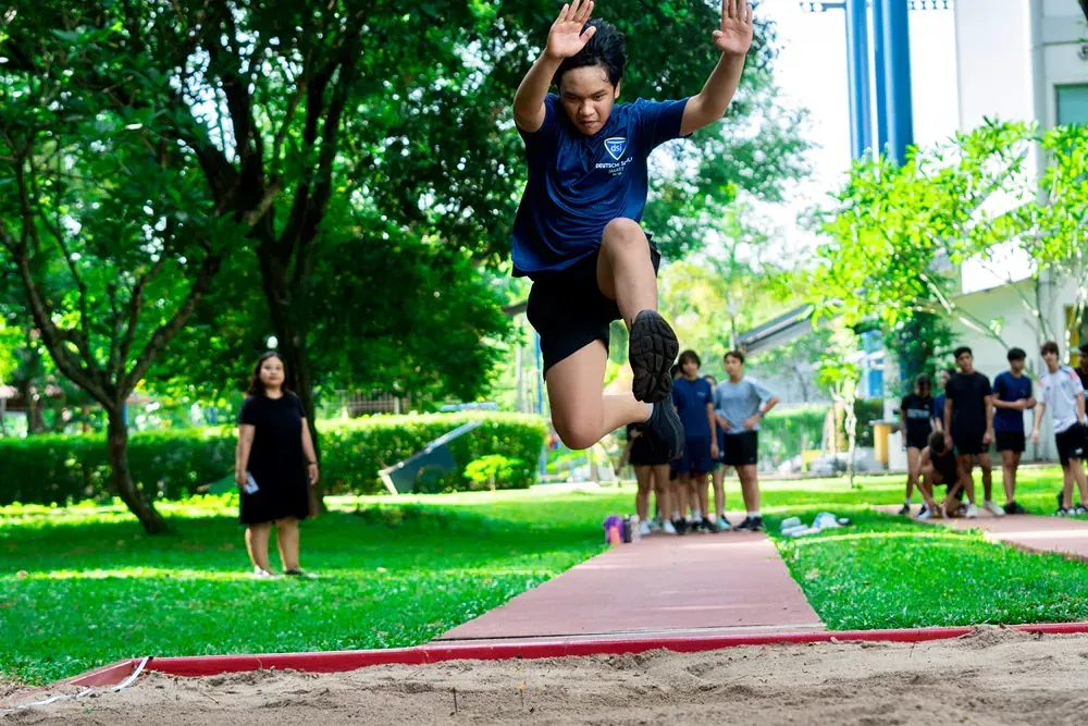 A man is jumping in the air while a group of people watch.
