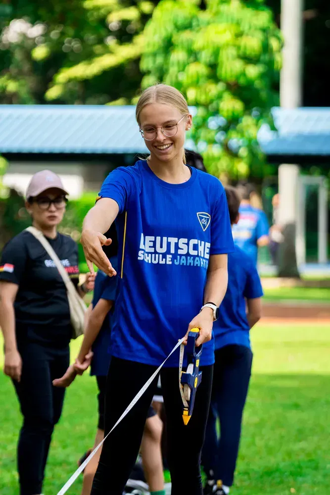 A woman in a blue shirt is walking a dog on a leash.