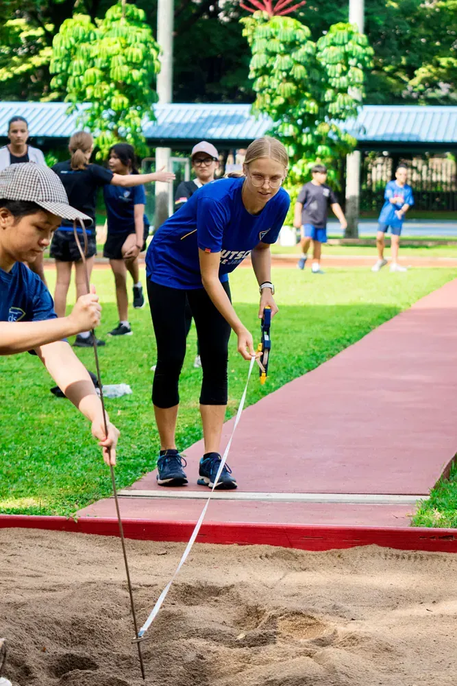 A woman is measuring the depth of a sand pit with a tape measure.