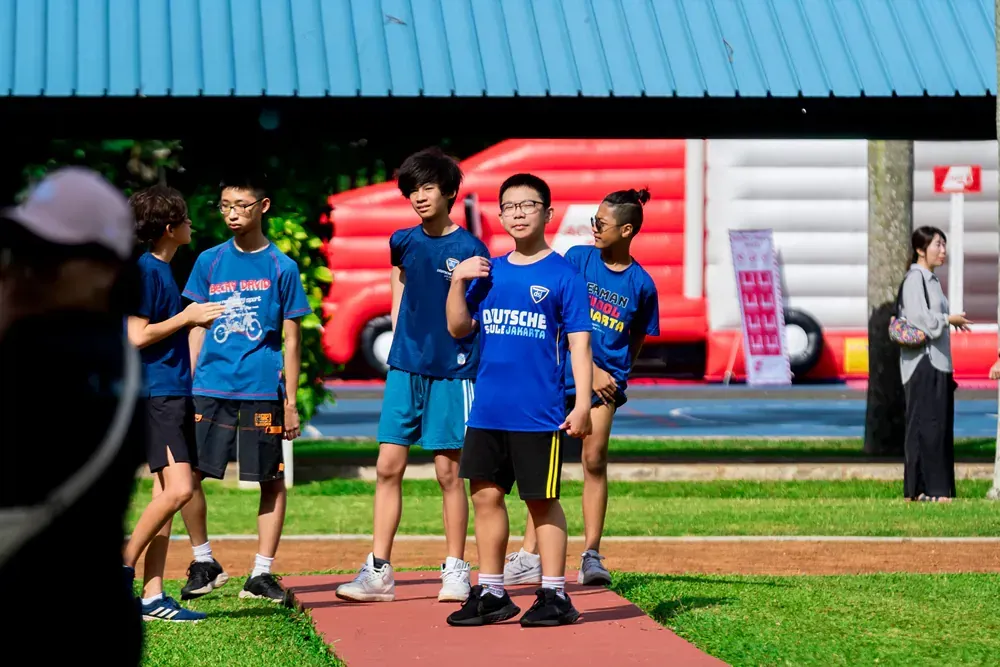 A group of young people are standing on a red carpet in a park.