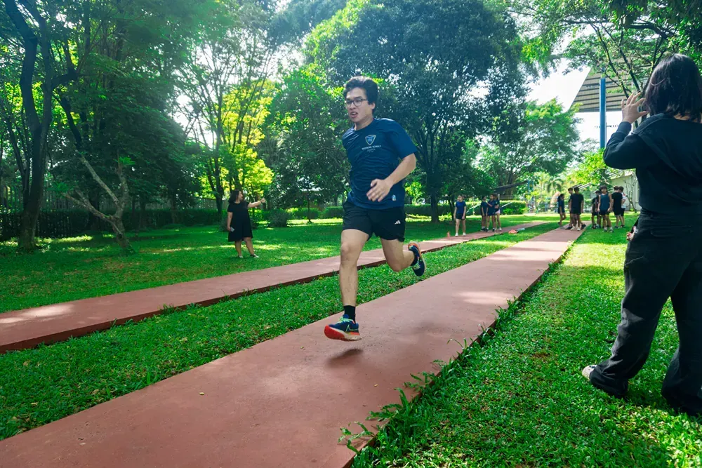 A man is running on a track in a park.