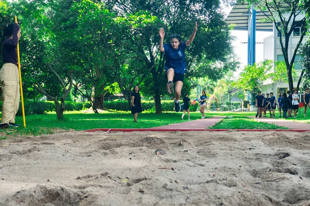 A woman is jumping in the air while competing in a long jump competition.