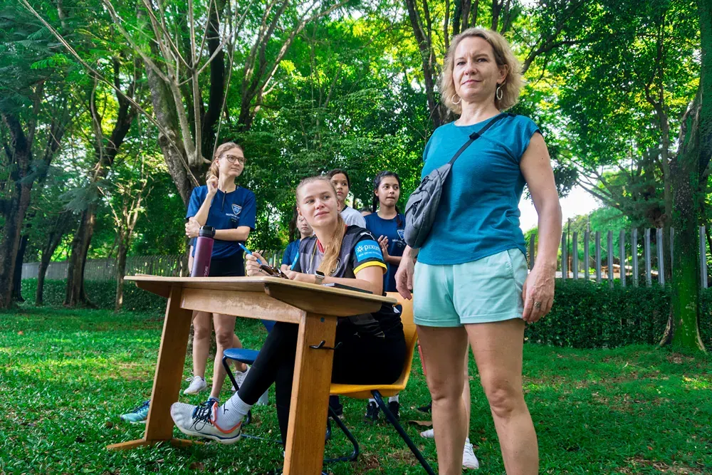 A woman is standing next to a wooden table in a park.