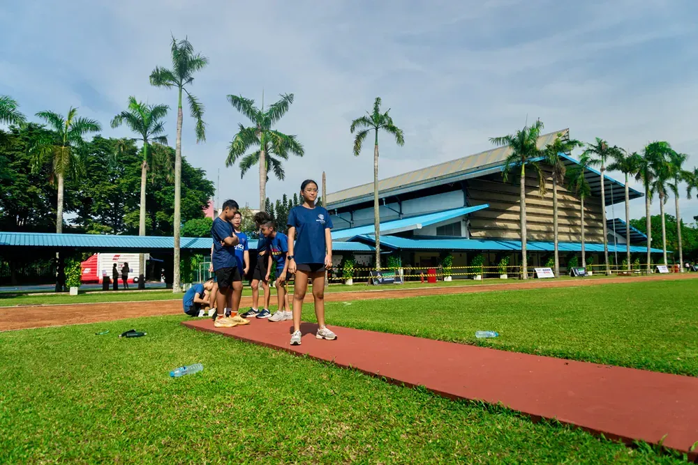 A group of people are standing on a track in front of a building.