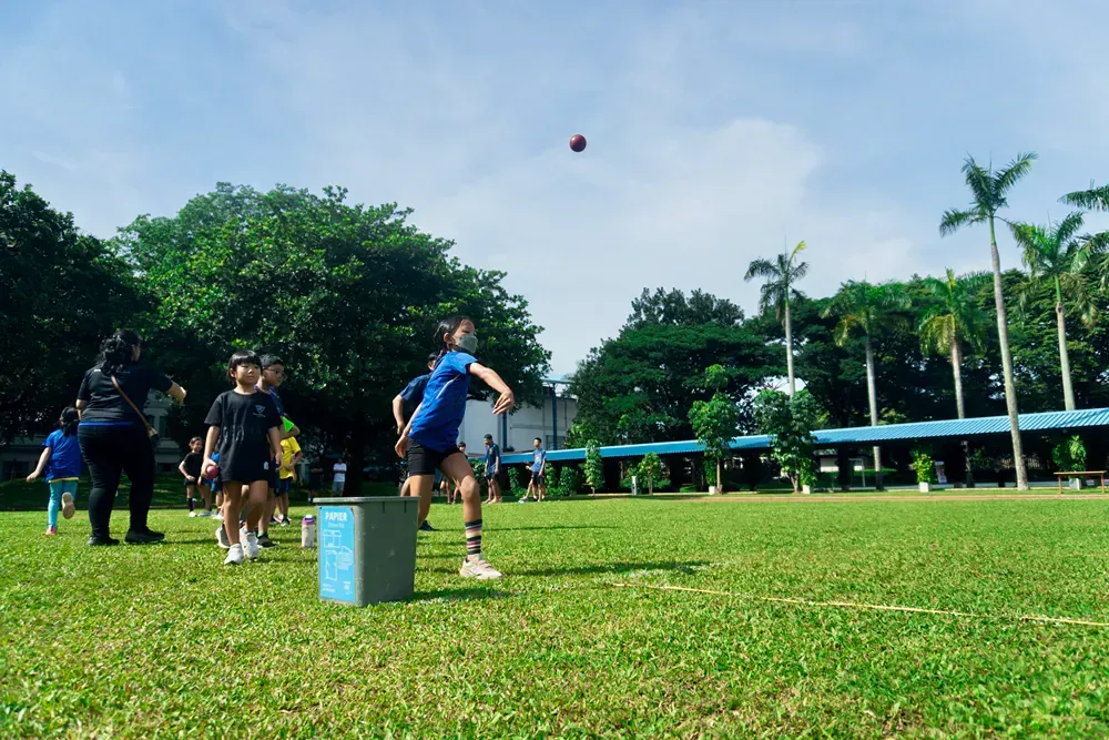 A group of children are throwing a ball in a field.