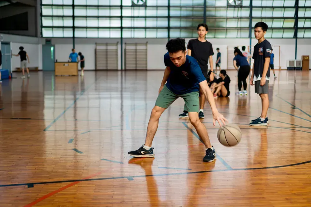 A group of young men are playing basketball in a gym.
