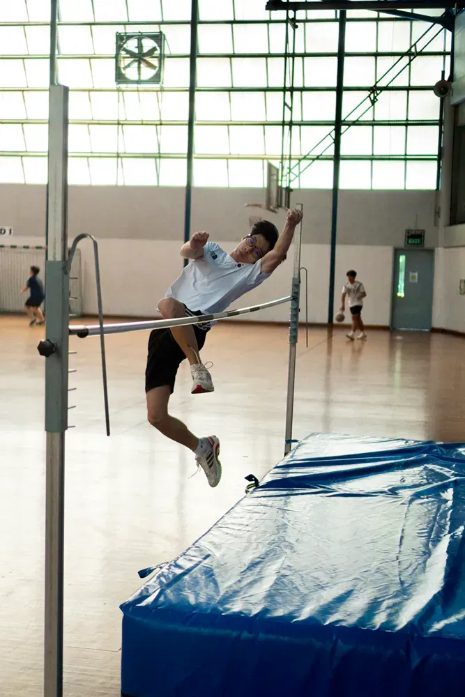 A man is jumping over a bar in a gym
